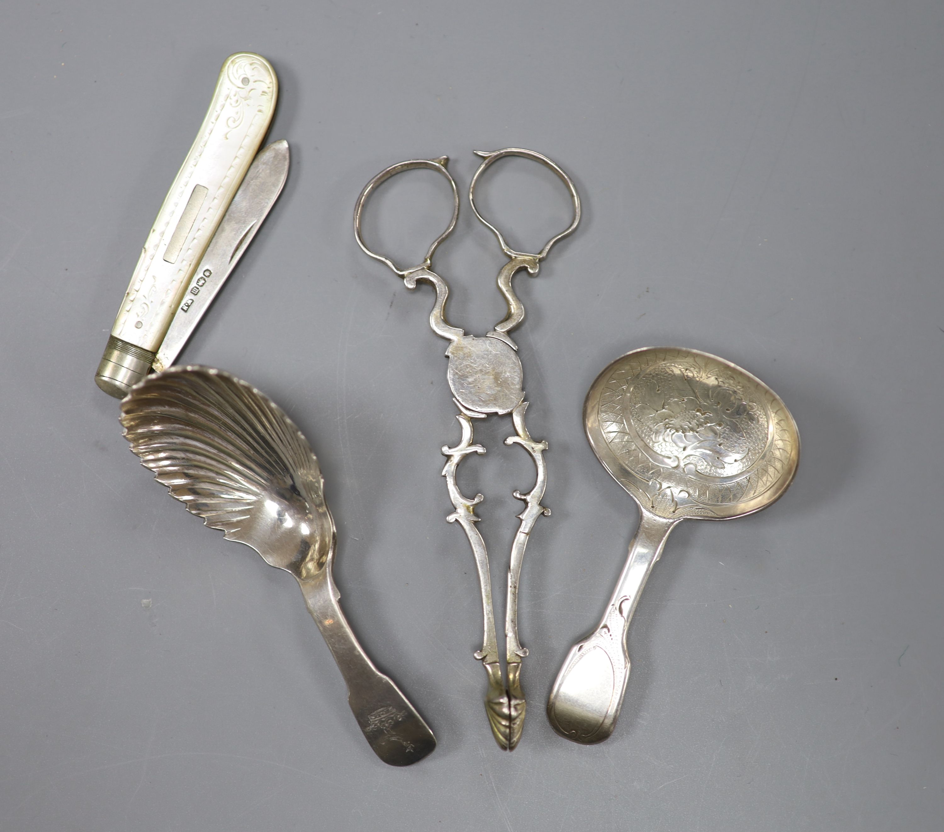 A pair of 18th century silver sugar nips, two later silver caddy spoons and a mother of pearl and silver fruit knife.